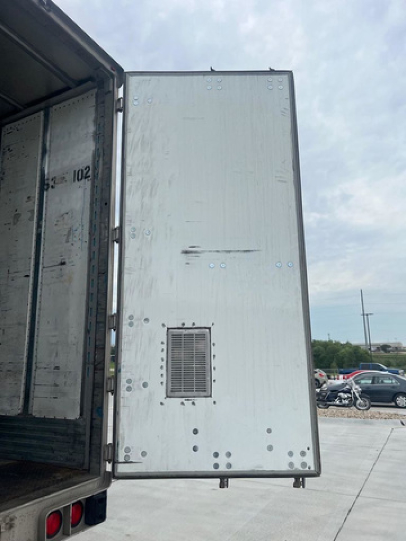 Utility van rear interior showing cargo area and exterior door with vents and riveted panels.