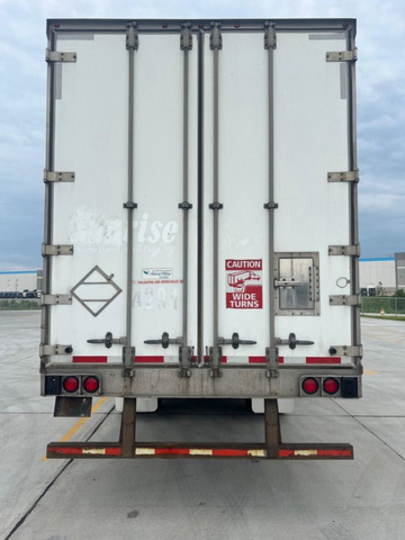 Rear view of a white utility van trailer with double doors, safety stickers, and latching hardware.