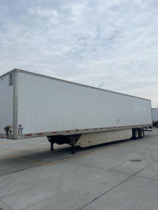 Utility van trailer side view showing a long white dry van with tandem axles and landing gear.