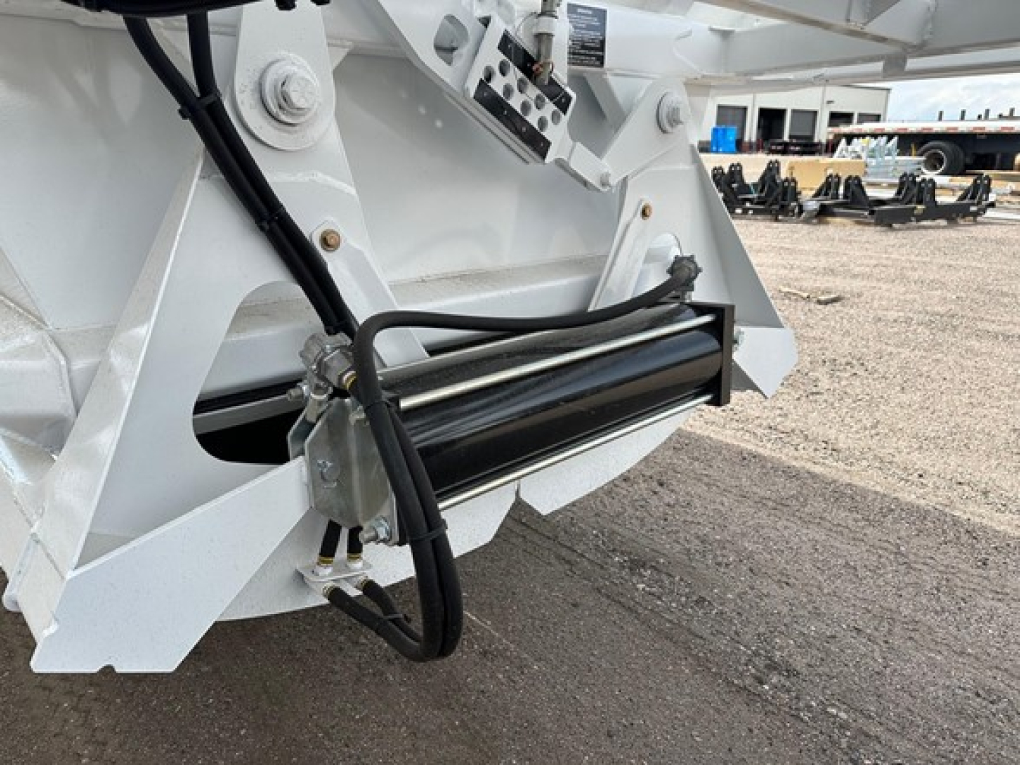 Bottom dump trailer hitch area showing hydraulic cylinder and hydraulic lines with white painted frame and control components.