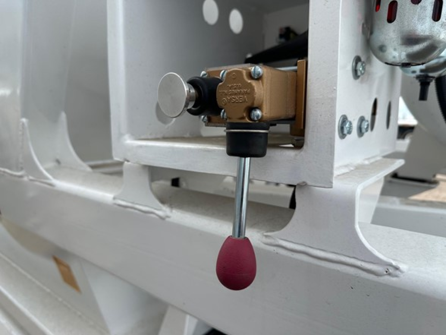 Bottom dump trailer draft showing a brown hydraulic valve with a red-pink lever knob and metal frame.