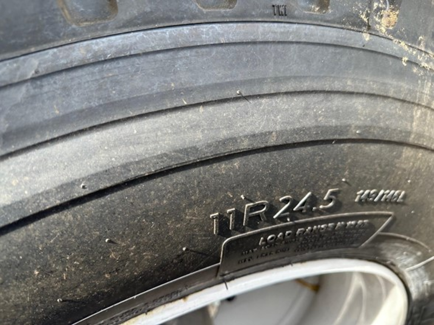 Trailer tire close-up with visible tire code TR245 and a metal badge, part of a Ranco air ride bottom dump trailer.