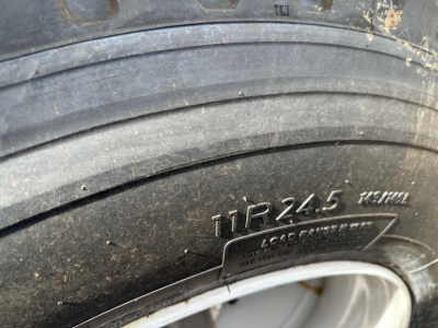 Tire close-up showing 11R24.5 load range marking and bead area; label plate partially visible: ‘LOAD RANGE’ and legible characters on tread.