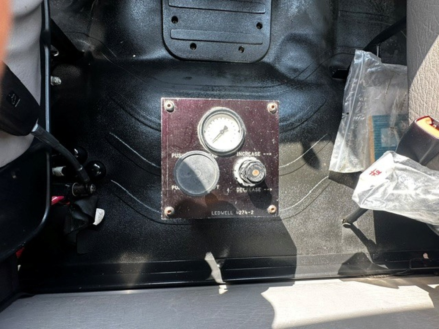 Dashboard panel with gauge and control labeled with PUSH, INCREASE, DECREASE, and other markings; surrounding metal surface and wiring visible.