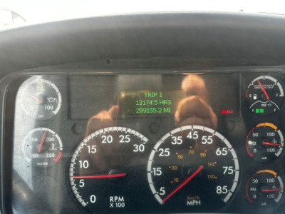 Dashboard of a Freightliner M2106 showing RPM gauge, speedometer, and digital trip odometer with green numbers in center.