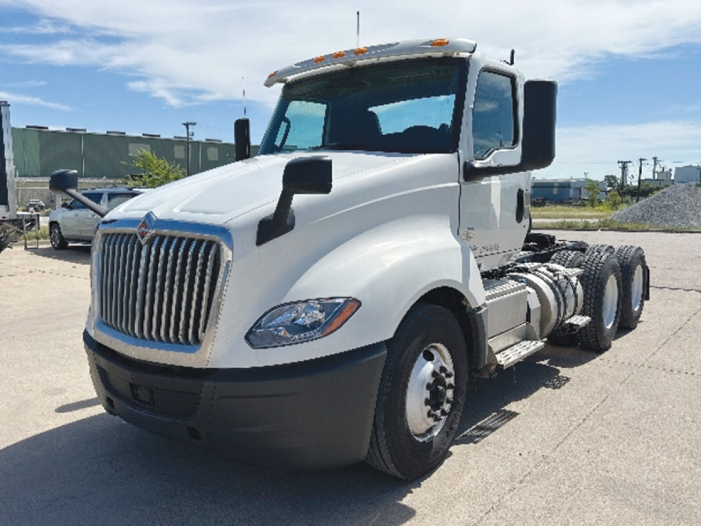 International LT625 sleeved front-left view showing cab, grille, and dual rear axles on a white day cab truck.