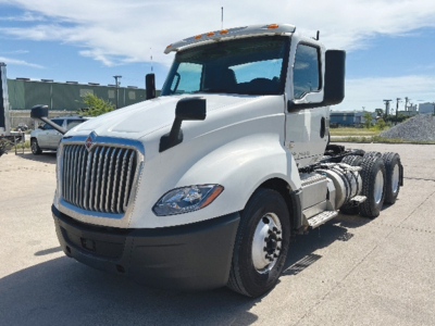 International LT625 sleeved front-left view showing cab, grille, and dual rear axles on a white day cab truck.