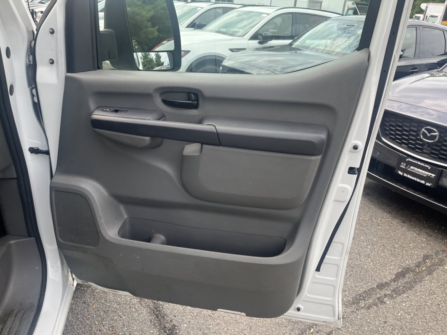 Truck door panel interior of a 2019 Nissan NV Cargo showing grey vinyl door cards and manual window crank.