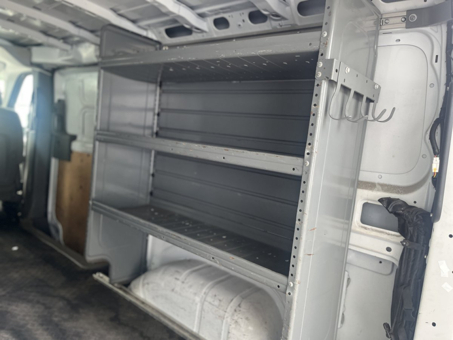 Shelving unit with multiple metal shelves inside a Nissan NV Cargo van cargo area.