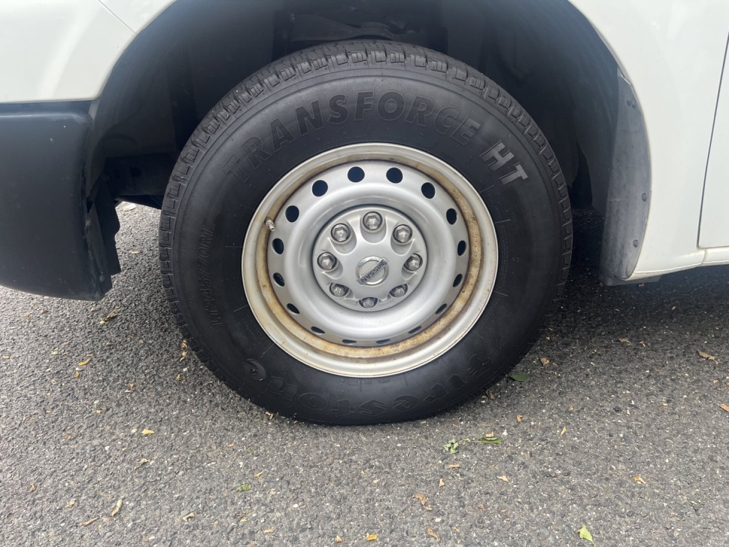 Tire and wheel of a Nissan NV cargo van showing steel rim and black tire with 'TRANSFORCE HT' sidewall.