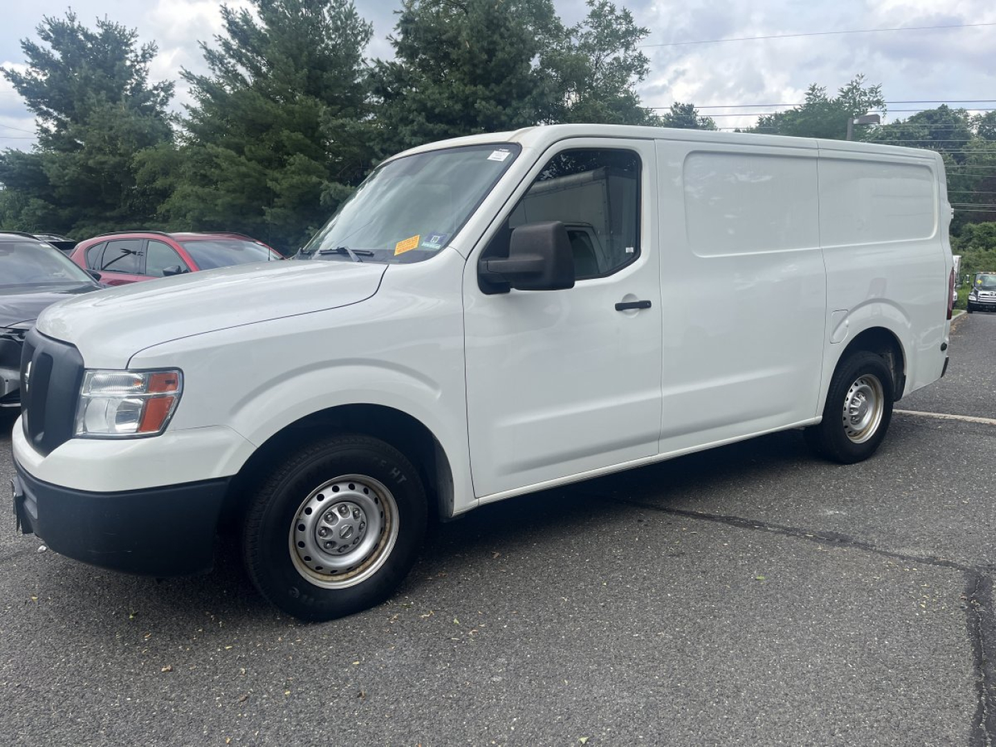 White 2019 Nissan NV Cargo van from a side-front view showing cargo van body with black grille and wheels.