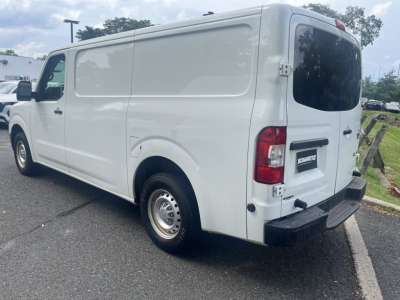 Cargo van rear-left three-quarter view of a 2019 Nissan NV Cargo, white, with rear doors, plain sides, black bumper, and factory steel wheels.