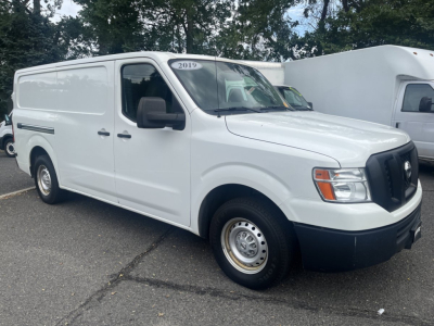 Nissan NV Cargo van in white, 2019 model year badge on windshield, front three-quarter view, plain black grille, black bumper, steel wheels, no cargo doors visible.