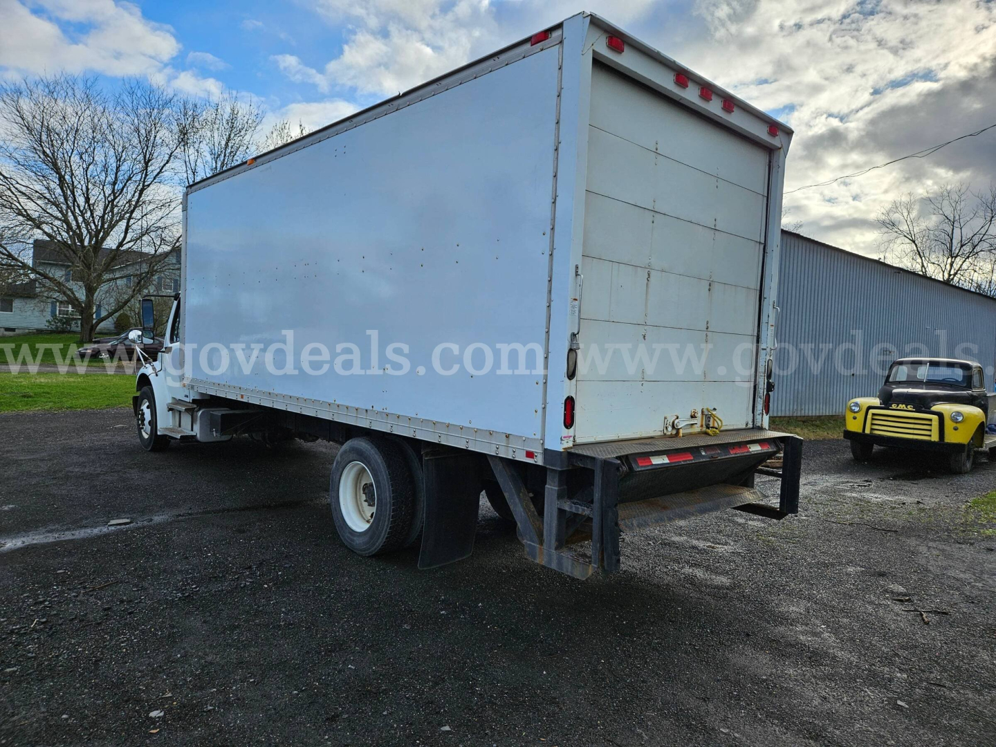 Box truck (Freightliner M2 106) rear/side view showing large cargo box and dual rear wheels.