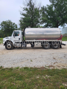 Truck side view: 2019 Freightliner M2 Tanker truck with stainless steel cylindrical tank, white cab. Visible text: 'MISSION MILLS' on door, 'tanker' body, nozzle hoses.