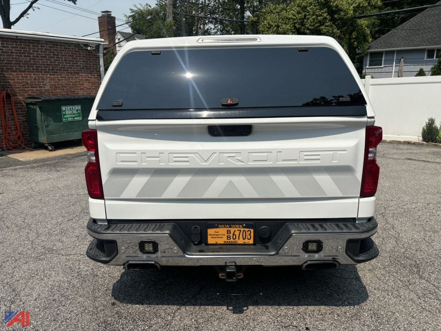 Chevrolet Silverado 1500 Crew Cab pickup with cap, rear view showing tailgate with CHEVROLET lettering, rear bumper, and orange New York plate.