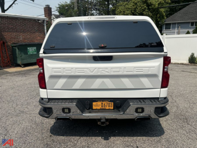 Chevrolet Silverado 1500 Crew Cab pickup with cap, rear view showing tailgate with CHEVROLET lettering, rear bumper, and orange New York plate.