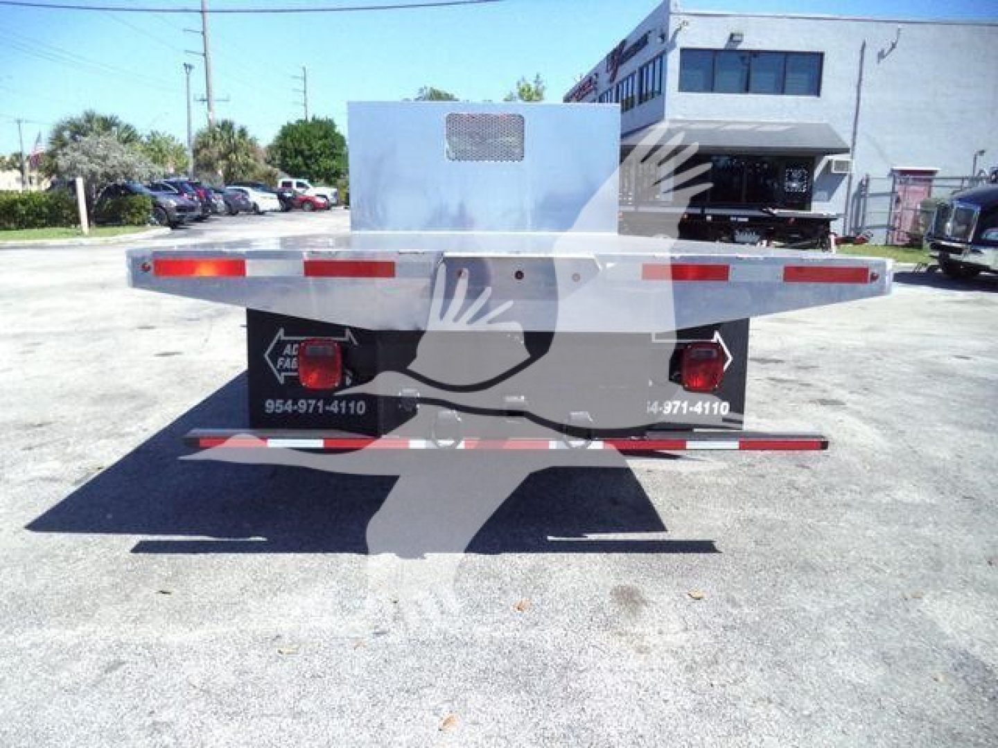 Flatbed truck rear view showing Silverado 6500HD flatbed with taillights and reflective stripes.