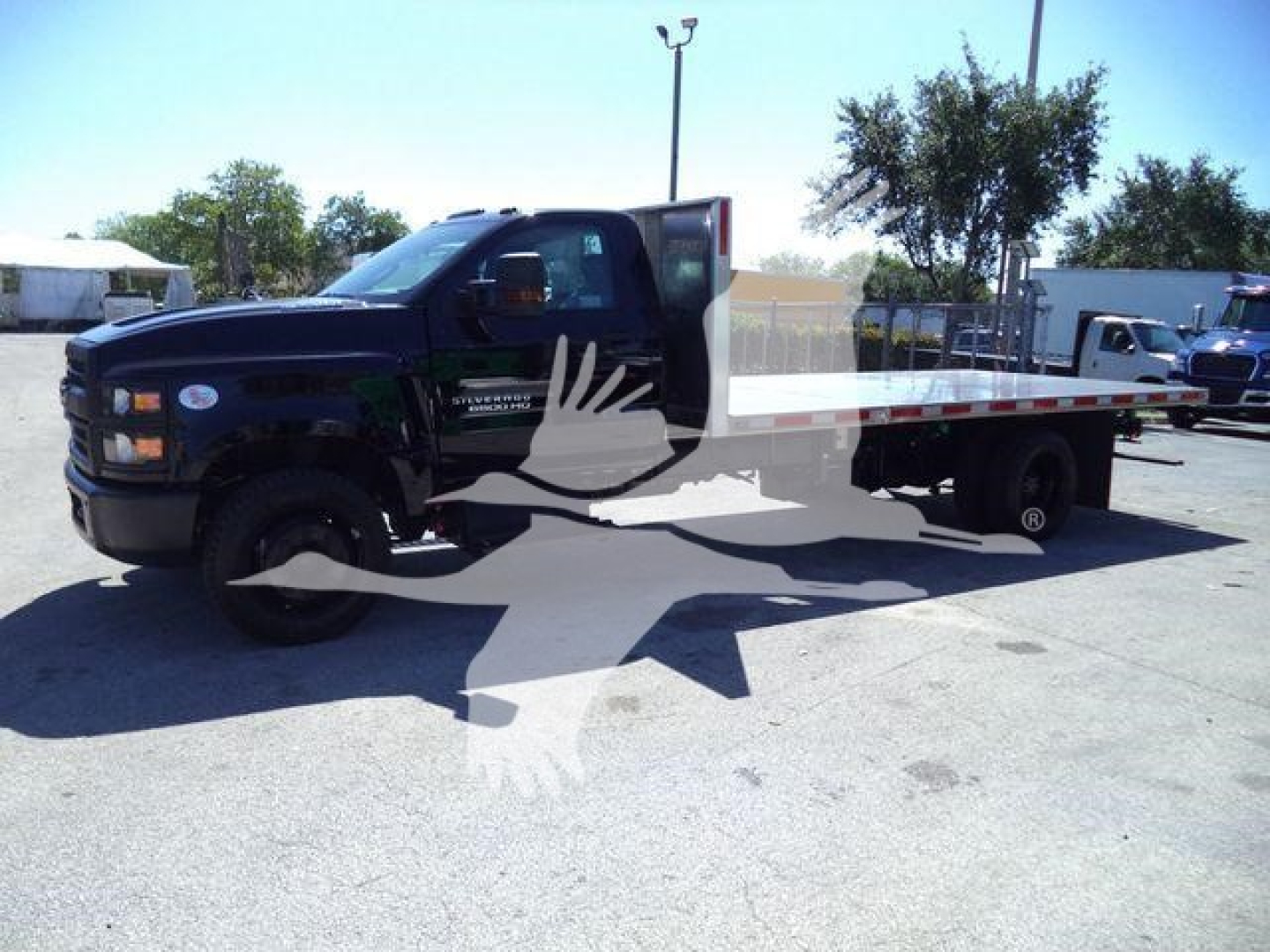 Chevrolet Silverado 6500HD flatbed truck in blue, side view showing flatbed and cab, dealership lot.