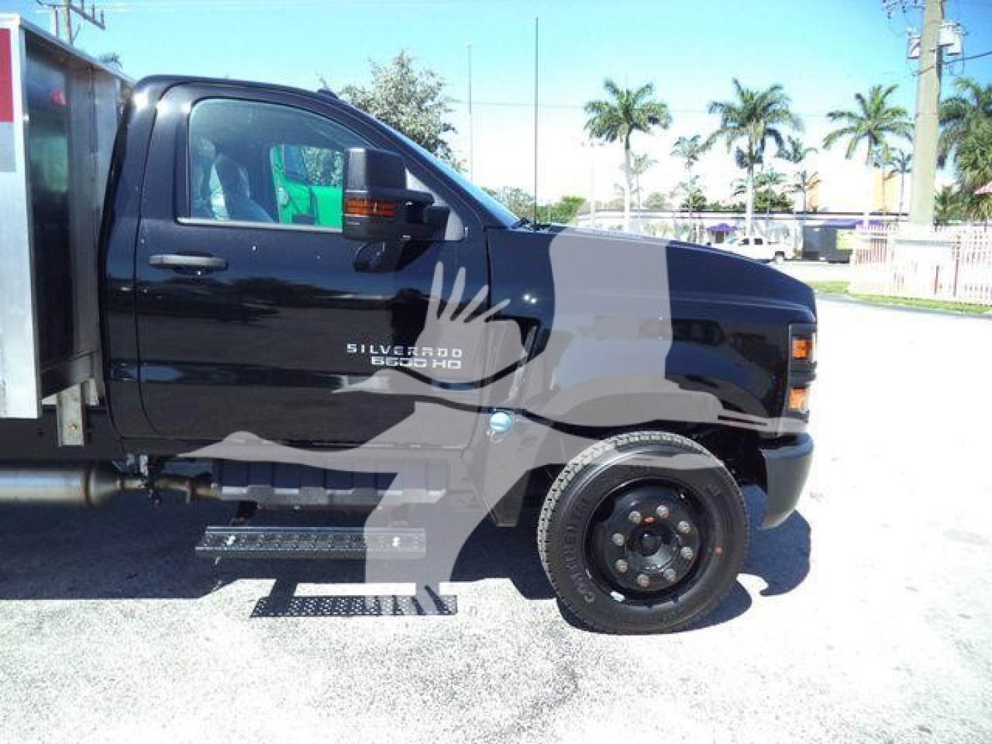Chevrolet Silverado 6500HD flatbed truck side view showing cab, door decal Silverado 6500HD, black exterior, running board, wheel, and flatbed area.