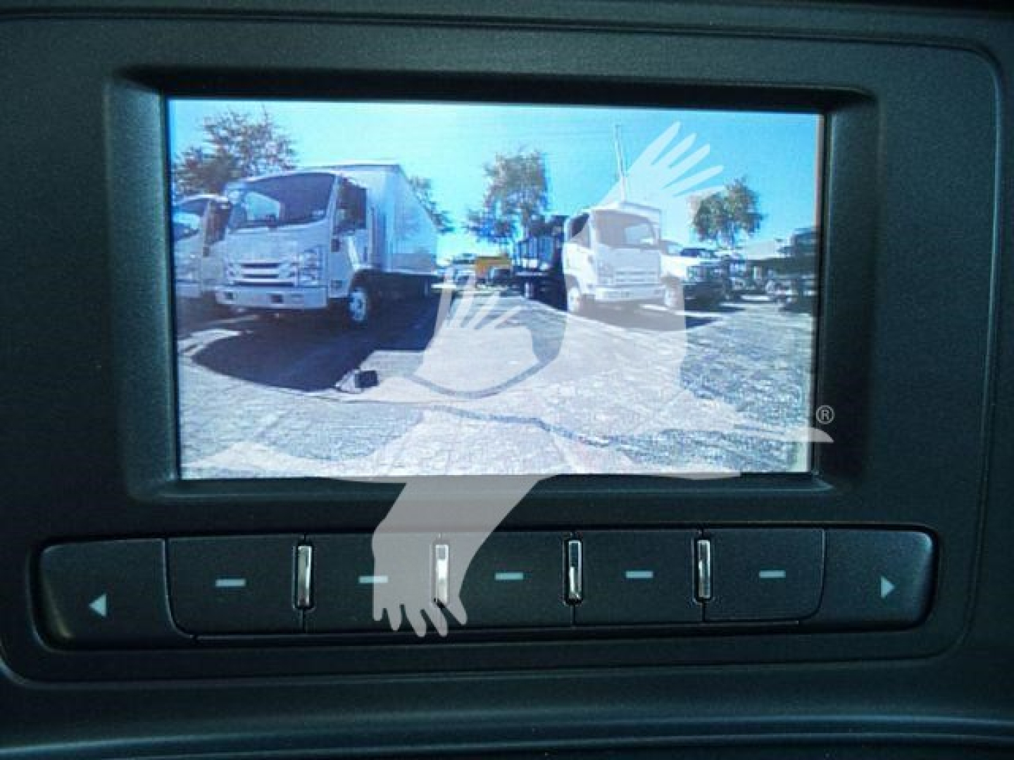 Flatbed truck interior monitor showing a rearview image of a Chevrolet Silverado 6500HD in a lot.