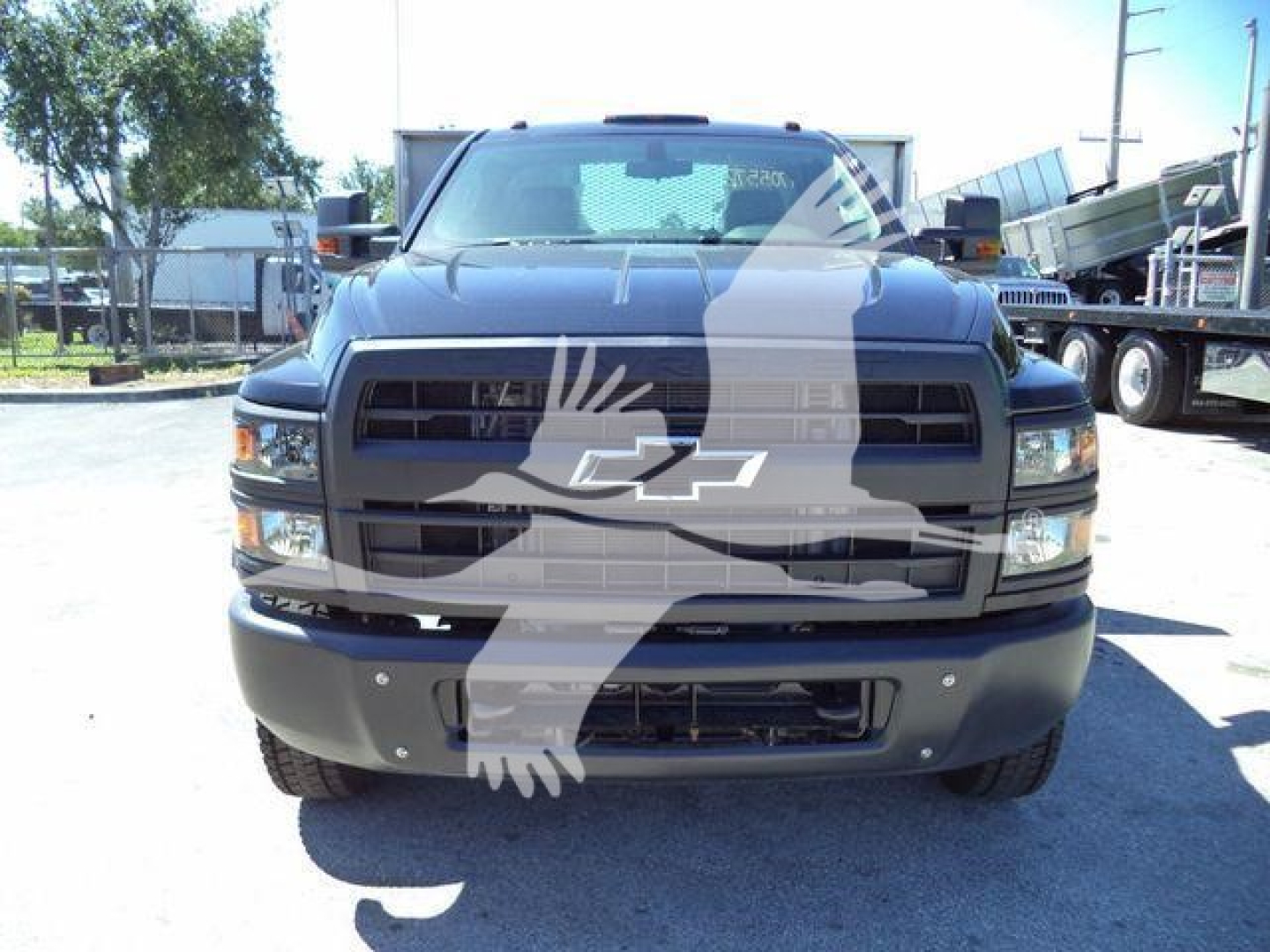 Front view of a 2023 Chevrolet Silverado 6500HD flatbed truck showing grille and bumper with Chevrolet emblem.