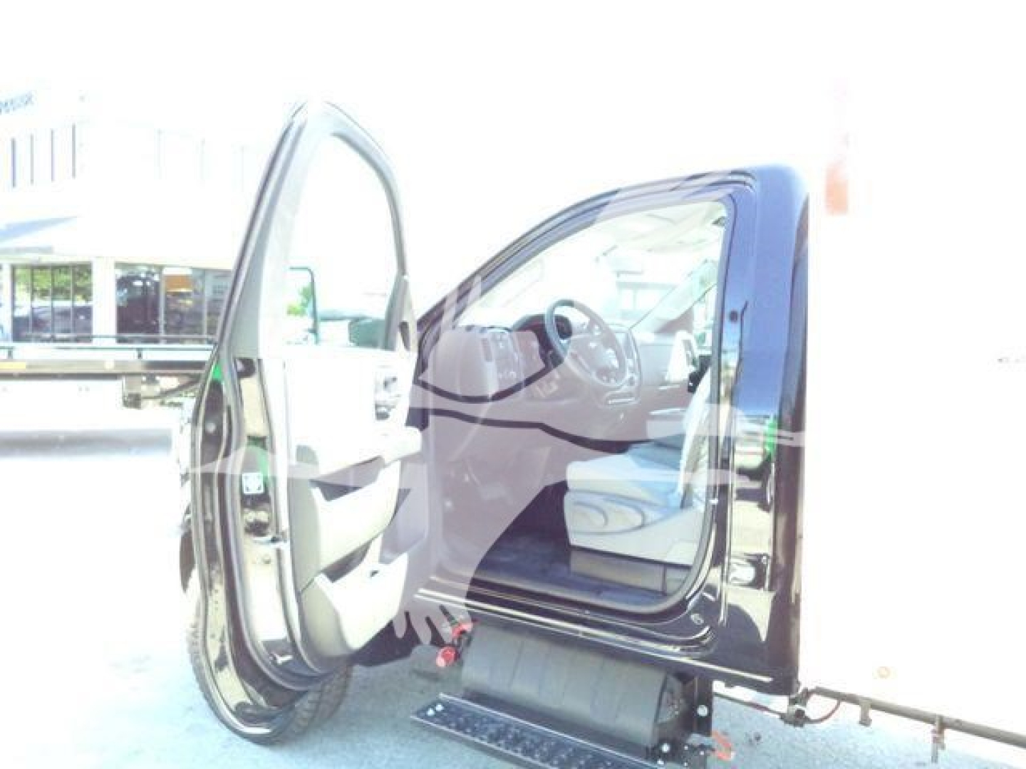 Truck cab interior with front passenger door open, showing steering wheel and dashboard in view; exterior black body with steps visible.