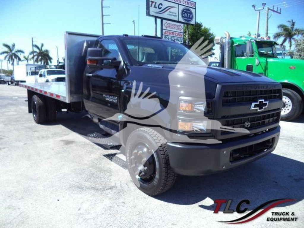 Chevrolet Silverado 6500HD flatbed truck in-service front-left view showing black cab and flatbed with GMC badge.