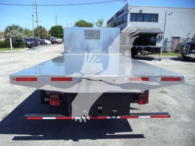 Flatbed truck rear view showing aluminum platform with rear bumper, taillights, and reflective striping on a 2023 Chevrolet Silverado 6500HD flatbed truck.