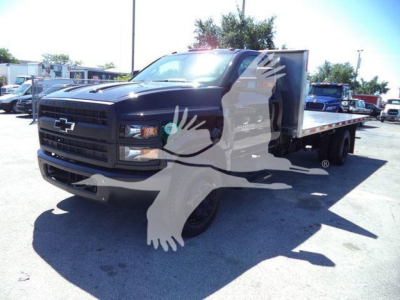 Chevrolet Silverado 6500HD flatbed truck front-left view showing black cab and aluminum flatbed at a dealership lot.