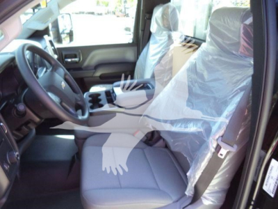 Truck interior showing driver seat with plastic protective cover, center console, and steering wheel in a Chevrolet Silverado 6500HD flatbed truck.