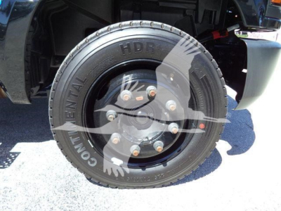 Truck wheel and tire close-up showing Continental tire with 'HD...', bolt pattern visible. Partial undercarriage of Chevrolet Silverado flatbed truck.