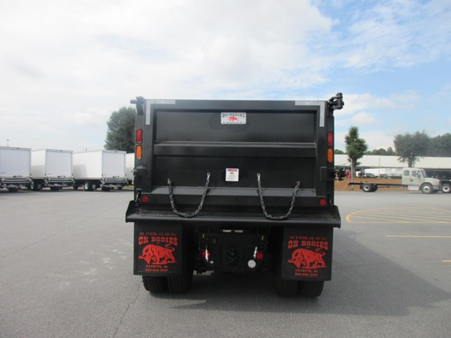 Dump truck bed of 2026 Freightliner 114SD rear view showing tailgate and mud flaps with red graphics.