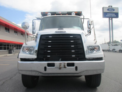 Front view of a new Freightliner 114SD dump truck showing large black grille, dual headlights, chrome bumper, and inspection mirrors.