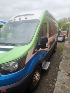 Ford Transit full-size van in a multicolor wrap showing front-left view with green hood, white roof, blue lower panel, black mirrors and side step.