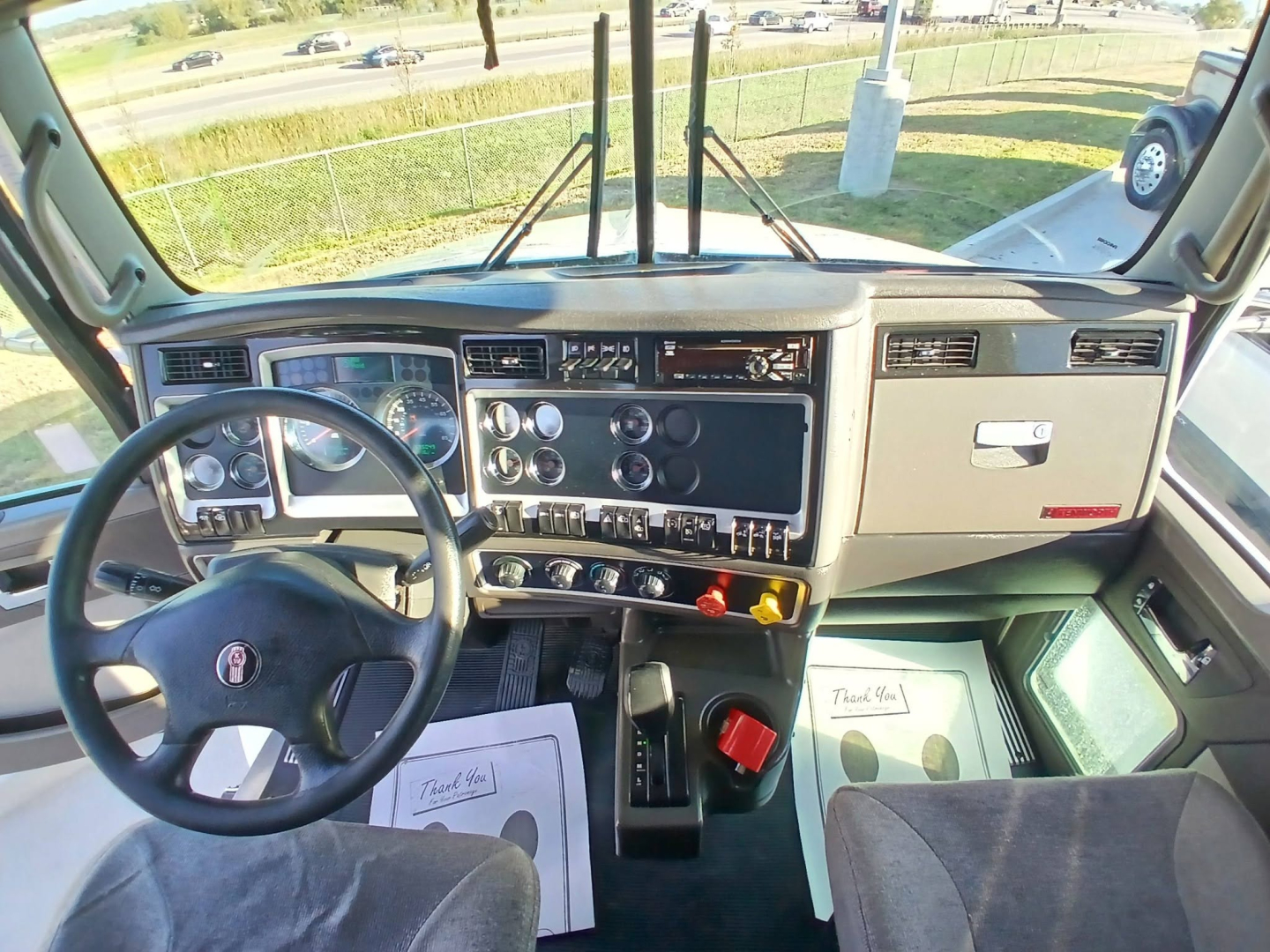 Kenworth T800 cab interior/dashboard view from driver seat with steering wheel, gauges, switches, and center console.