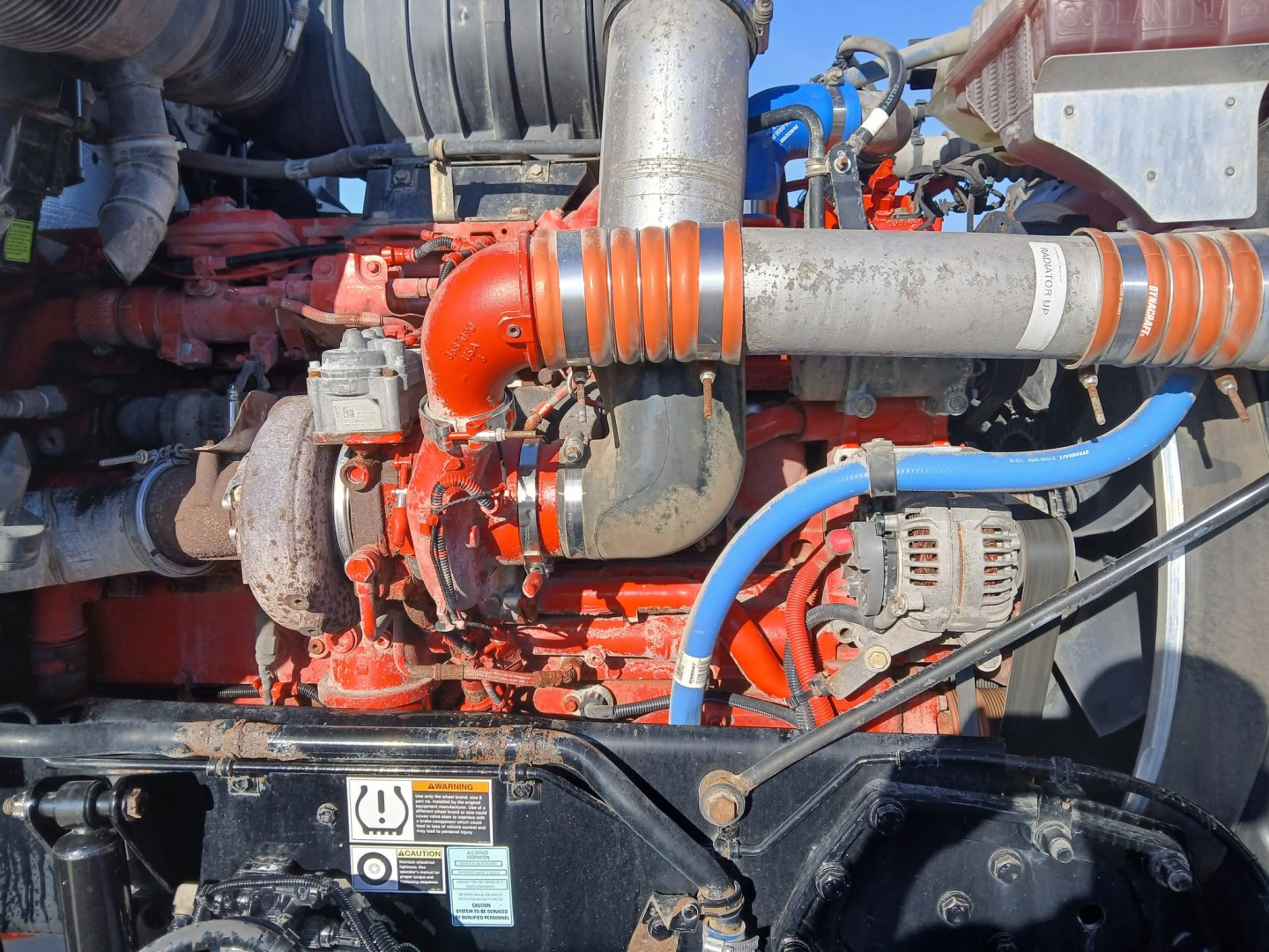 Kenworth T800 engine bay showing red engine and turbo piping with blue hose and alternator