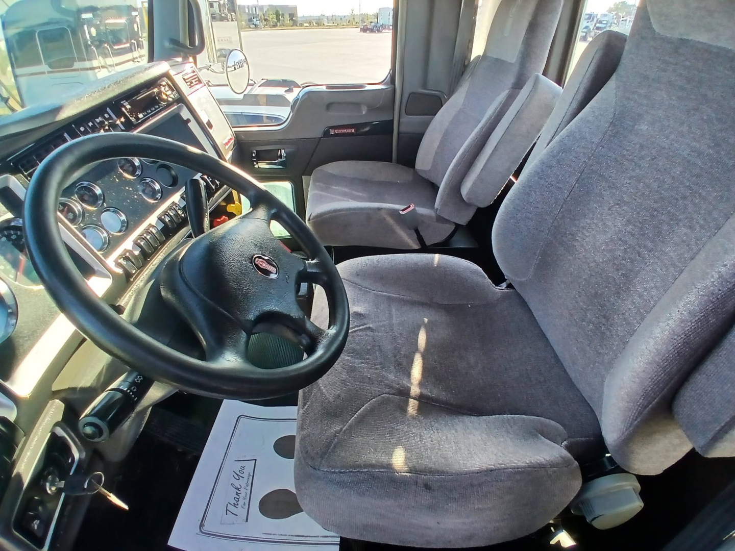 Kenworth T800 cab interior showing steering wheel dashboard and front seats.
