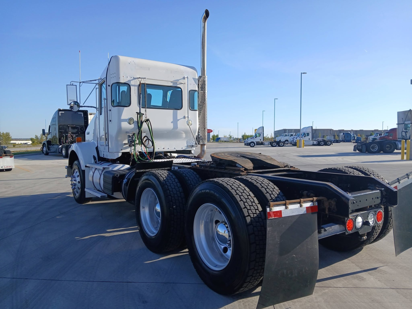 Kenworth T800 tractor chassis rear view 3-axle configuration with sleeper cab and dual rear axles, chrome exhaust stack, and mudflaps.