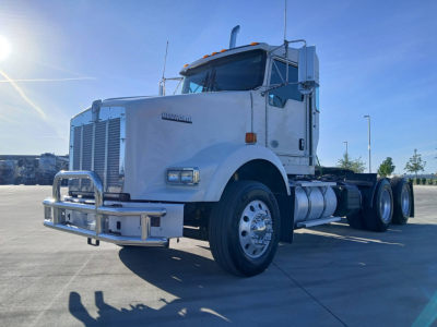 Kenworth T800 conventional sleeper truck in a parking lot showing front grille, bumper guard, and dual rear axles.