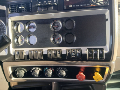 Kenworth T800 dash panel showing gauges and switches with climate controls and red/yellow hazard knobs.