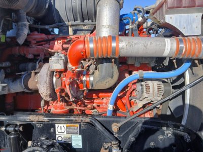 Kenworth T800 engine bay showing red engine and turbo piping with blue hose and alternator