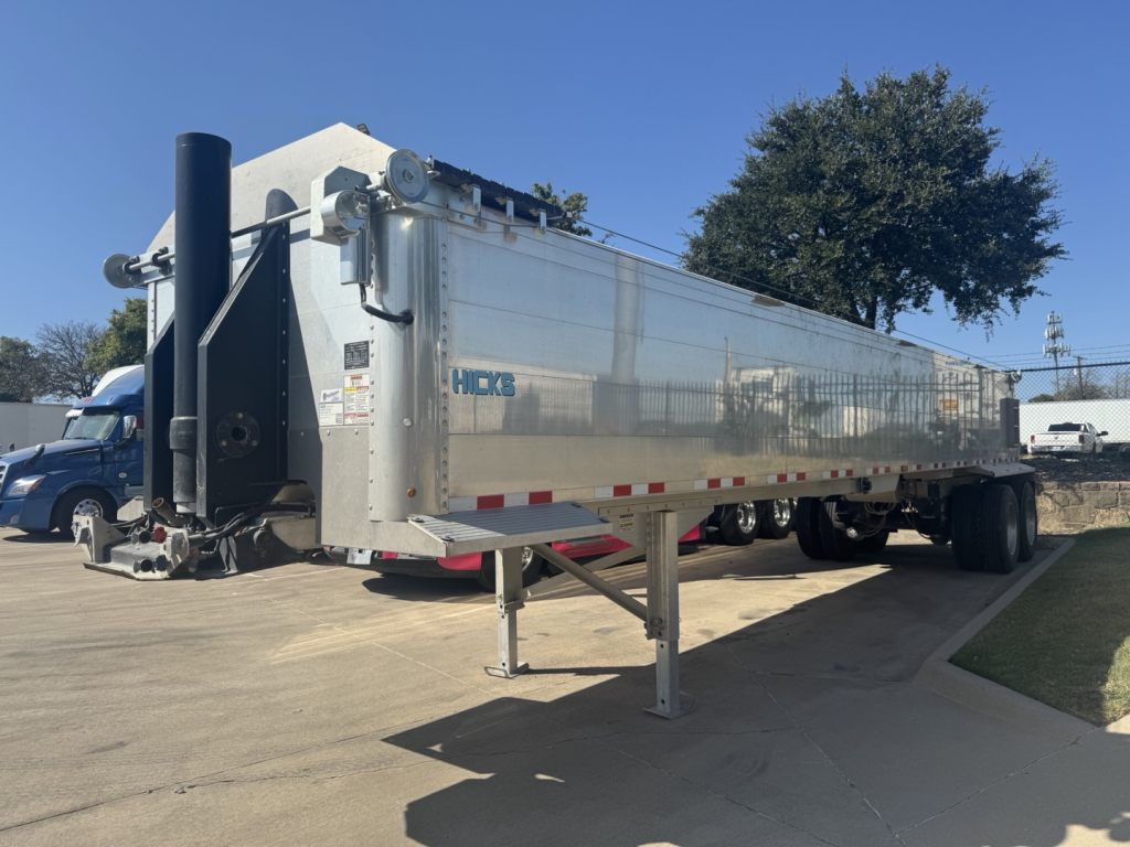 Dump trailer showing Hicks SL3932 with aluminum side panels and dual rear axles, front landing gear extended, VIN 1H9A39A25VM686030 visible on trailer.