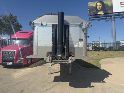 Dump trailer hitch view showing vertical exhaust/stack assembly and rear access doors with metal ramp supports.
