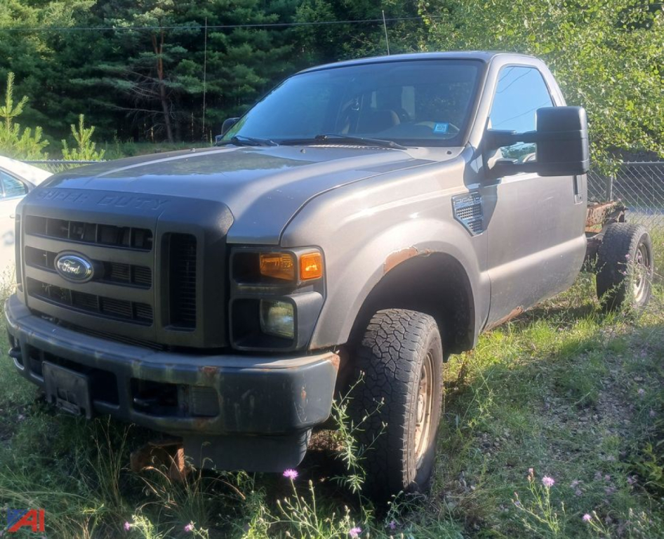 Ford F-250 Super Duty cab and chassis truck, front left view, grey exterior with large side mirrors, no bed installed.