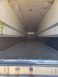 Interior of a used utility trailer 3000R with empty cargo area, ribbed floor, side E-tracks along the walls, light above, rear entry open.