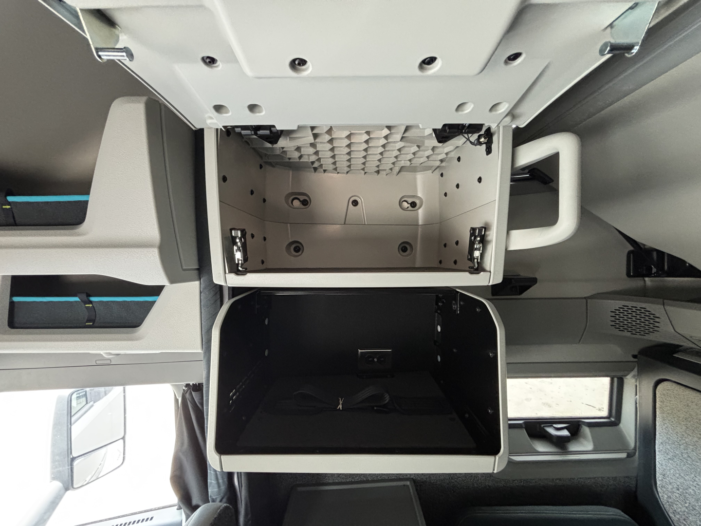 Cab interior of a 2027 Volvo VNL64T860 showing open center console/storage with dashboard pockets and overhead cab area.