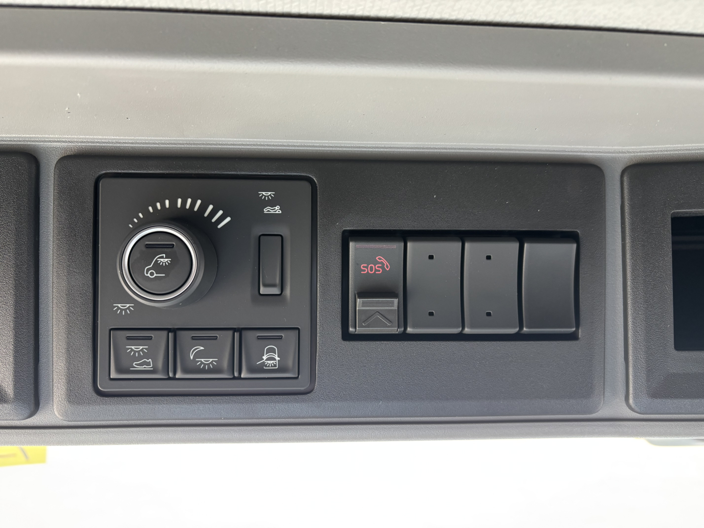 Volvo truck dashboard controls and switches in cabin showing climate/air functions and SOS button.