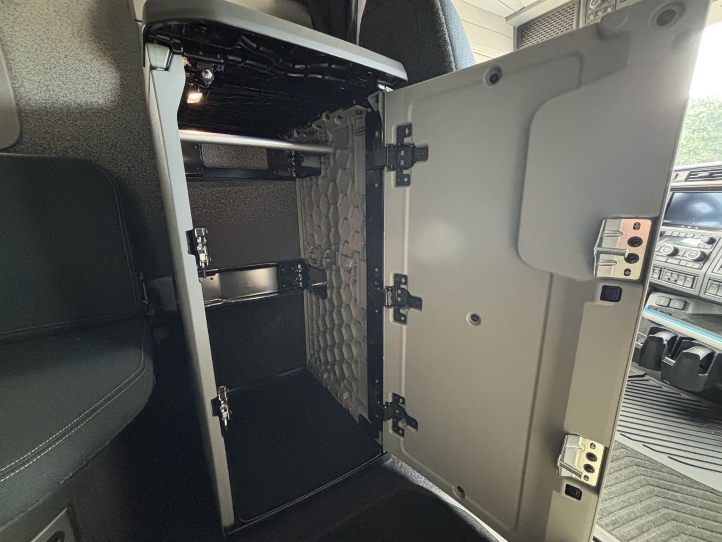 Volvo VNL64T860 sleeper cab interior showing empty storage cabinet with door open and latches visible.