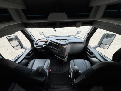 Volvo VNL64T860 truck cabin dashboard with steering wheel, two front seats, large windshield, and mirrors visible.